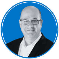 The image shows a smiling middle-aged man with glasses wearing a black suit against a bright blue background.