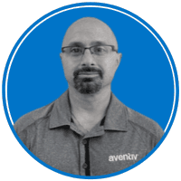 The image shows a middle-aged man with glasses and a beard wearing a gray shirt with the Avenir logo, against a bright blue background.