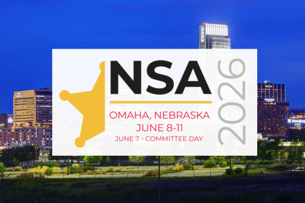 A large billboard displaying the NSA logo and event details against the backdrop of a city skyline at night.